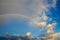 clouds with a rainbow. Multicoloured curved strip in the firmament, as a consequence of the refraction of sunlight in raindrops.