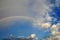 clouds with a rainbow. Multicoloured curved strip in the firmament, as a consequence of the refraction of sunlight in raindrops.