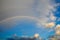 clouds with a rainbow. Multicoloured curved strip in the firmament, as a consequence of the refraction of sunlight in raindrops.