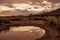 Clouds reflected in rain puddle in dirt road California valley view hill ridge