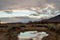 Clouds reflected in rain puddle in dirt road California valley view hill ridge