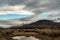 Clouds reflected in rain puddle in dirt road California valley view hill ridge