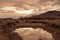 Clouds reflected in rain puddle in dirt road California valley view hill ridge