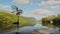 Clouds reflecting on lakes surface with beautiful british landscape reflections of lone tree and cl