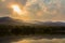 Clouds and sunbeam over mountain and lake