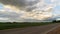 clouds at sunset over an asphalted empty highway that runs between rural fields