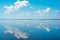 Cloudscape. clouds in blue sky and reflection in a large lake. White cumulus clouds in sky over blue sea water landscape, big