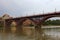 Cloudy autumn day in Maribor. Old Bridge over Drava River reflected in water. Group of white swans swimming near the river bank.