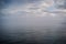 Cloudy blue minimalist seascape. Deserted space. Horizon line. re island bridge in the background