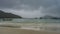 Cloudy day on a tropical beach. Turquoise waves roll on wet sand