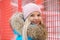 Cloudy outdoor winter portrait of young happy adorable woman in bright cyan coat posing in winter city park against bright red and