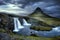 Cloudy overcast day of the Kirkjufellsfoss Waterfall with Kirkjufell mountain in the background in Iceland.