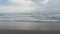 Cloudy sea by sandy beach. A view of a cloudy morning and a rough sea waves on the beach. A concept of cold season for