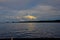 Cloudy sky at dusk over lake. A thin strip of island on the horizon