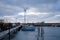 Cloudy sky with large wind mill in the background and small boats in front