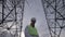 Cloudy sky and a male technician working between tall ETL towers