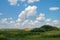 Cloudy summer sky over the meadow hilly valley of the reserved places of Russia. Landscape field and grass