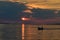 Cloudy sunset above Vrsi Mulo bay in Croatia with silhouette of fisherman an his boat sailing home