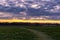 cloudy sunset over green field 