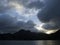 Cloudy sunset over mountain lake. Spectacular stormy clouds under sunlight.