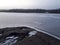 Cloudy, winter day at the lake. Frozen white lake and cold brown stone.