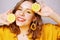 Clouse up of a girl with a lemon. A girl in a bright yellow dress, with yellow earrings, holds a lemon. Sincere smile.