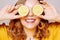 Clouse up of a girl with a lemon. A girl in a bright yellow dress, with yellow earrings, holds a lemon. Sincere smile. covering ey