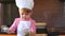 Clouse-up portrait small child in chef suit helps her mother cook in the kitchen