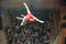 A clown acrobat performs with a number in front of the public.