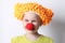 Clown baby girl with a red nose in a funny cap