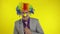 Clown businessman entrepreneur boss in wig show thumb up. Yellow background
