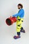 The clown firefighter holds a fire barrel in his hands, extinguishes the fire