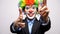 Clown woman in business suit and colorful wig making gun signs from hands