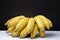 Clsoeup shot of a bunch of ripe yellow bananas on a white surface with a black background