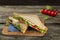 Club sandwich with chicken breast, tomato, cheese and green salad on the wooden background