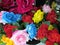 A cluster of artificial fake assorted colorful vibrant rose flowers on display