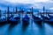 Cluster of boats in a body of water with a skyline of Venice in the background.