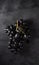 A cluster of juicy black grapes lies  on a dark gray table