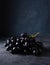 A cluster of juicy black grapes lies  on a dark gray table