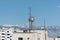 Cluster of mobile network broadcast cell repeaters on roof of building in city.