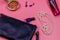Clutch bag, pearl necklace, earrings, nail polish, rouge balls and bottle of perfume on pink background. Beauty and fashion
