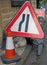 Clutter of temporary warning and direction signs at the side of a narrow country road while repair work is being carried out