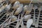 Cluttered array of forks and spoons on mesh rack.