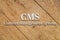 `CMS, Content Management System` white text on a wooden background.