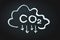 CO2 sign and arrows pointing down and cloud on black memo board. Reduce carbon dioxide emissions, limit global warming
