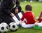 Coach Coaching Preschool Soccer Boy. Youth Coach Explaining Tactics Basics of Soccer on Tactic Board