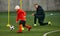 Coach controlling movements. Little boy, child, football player in uniform training outdoor at sports stadium. Dribbling
