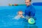 Coach teaches the baby to swim in the pool. baby splash in the water in the pool. The concept of a healthy