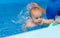 Coach teaches the baby to swim in the pool. baby splash in the water in the pool. The concept of a healthy