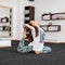 Coach young woman practicing yoga pose in fitness studio. Girl makes stretching indoors